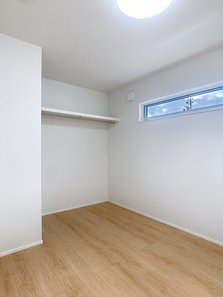 横長窓とオープンクローゼットのある洋室